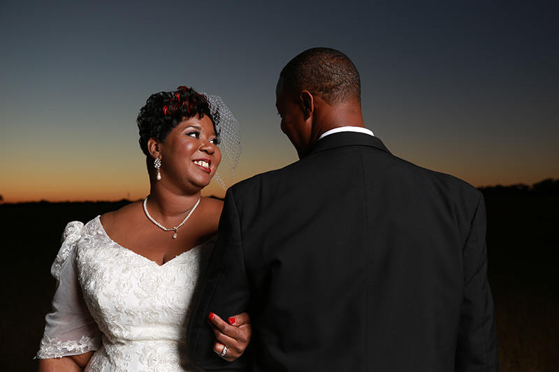 bride and groom posing and interlocking arms, smiling