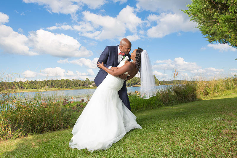 bride and groom posing in front of lake