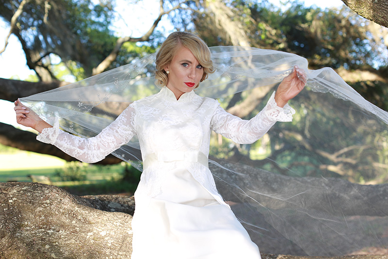 bride posing with veil and wedding dress outdoors