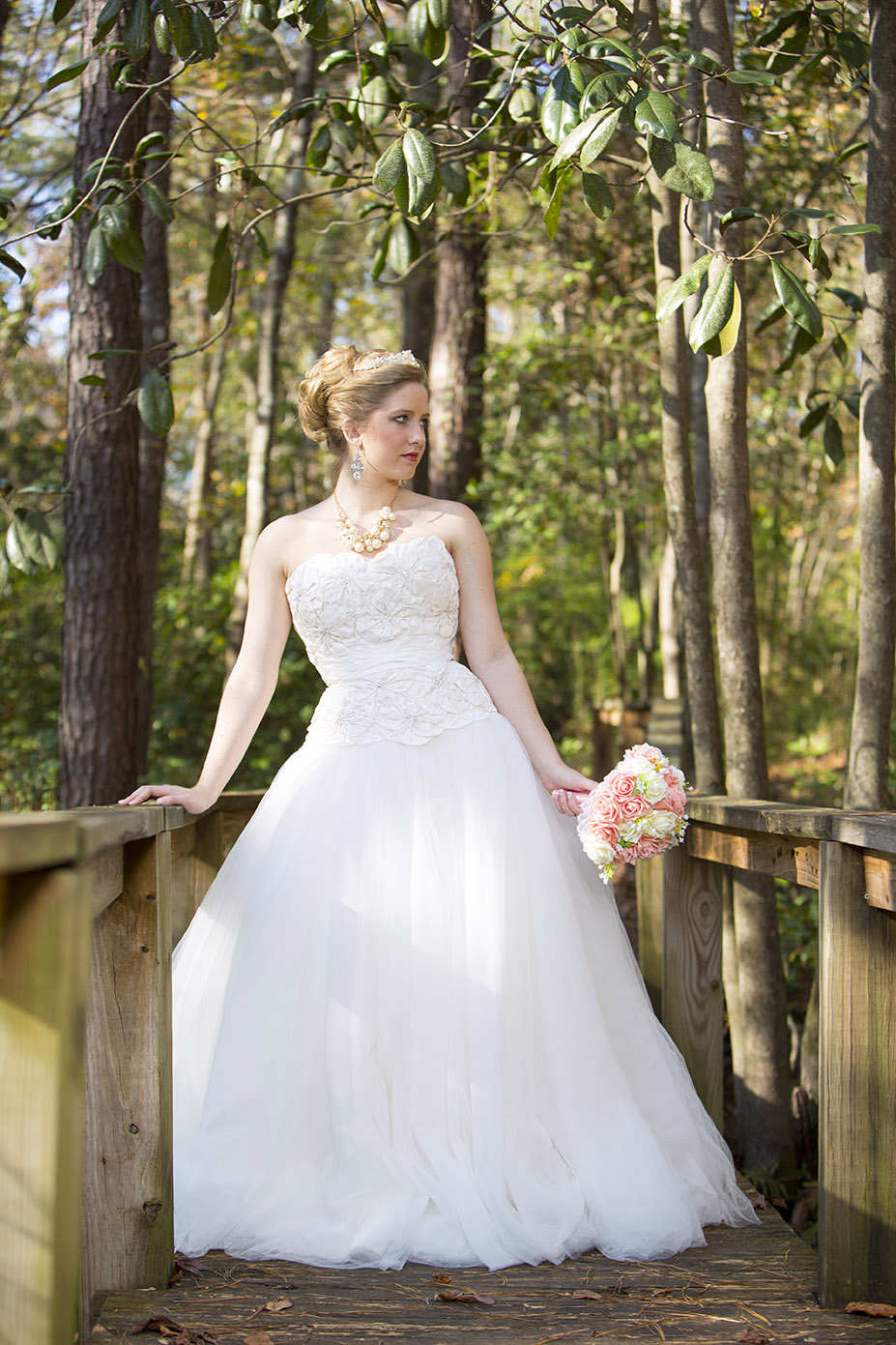 bride posing around trees with flowers in hand