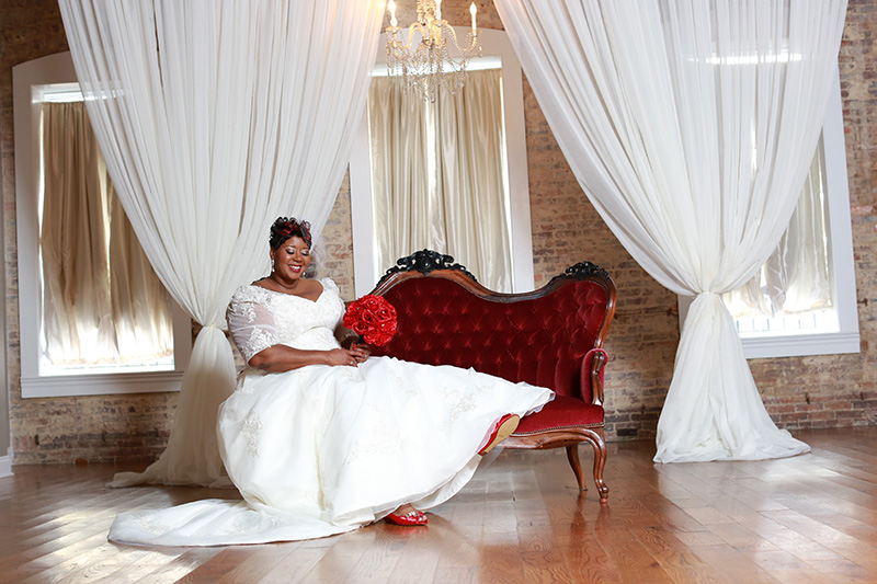 bride posing and smiling on couch in wedding dress