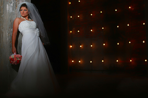 bride leaning against wall with patterned background and lights