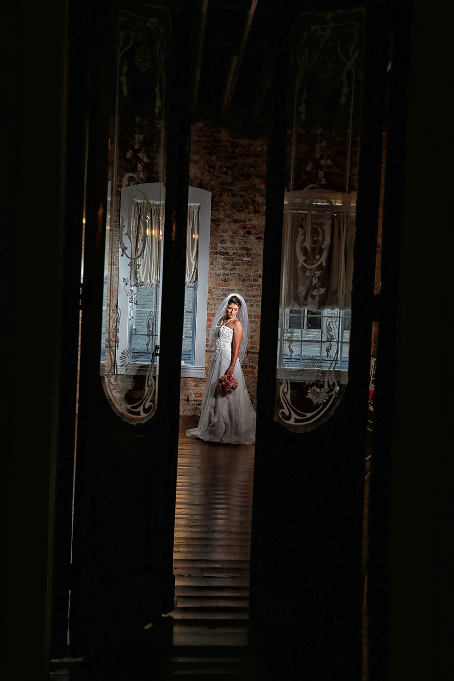 bride posing between two french doors with a bouquet in hand