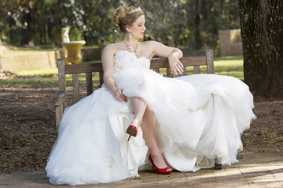 bride posing on a bench with trees in background for wedding photo