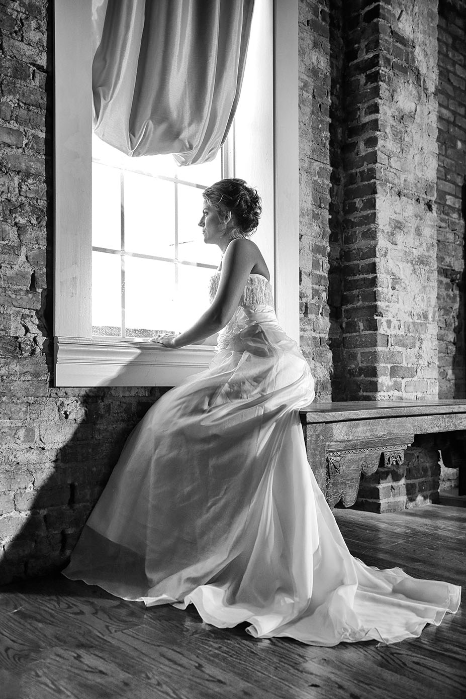 bride posing looking out of a window in wedding dress